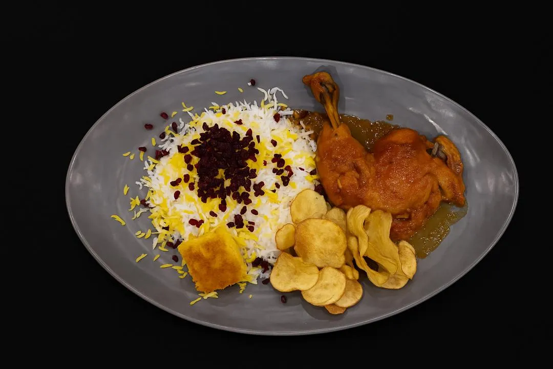 زرشکپلو با مرغ کالانتر؛ برنج ایرانی زعفرانی با زرشک تازه، مرغ خورشتی لذیذ و تهدیگ ترد طلایی.
